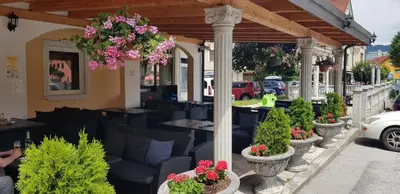 a restaurant with chairs and flowers on a patio at Hotel Razgorsek in Velenje