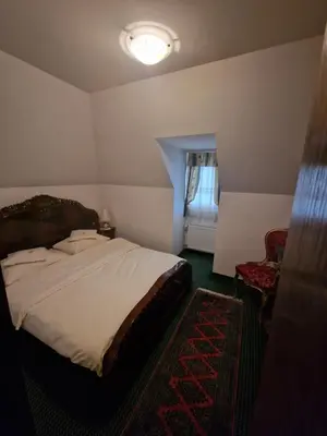 a bedroom with a bed and a chair and a window at Hotel Razgorsek in Velenje