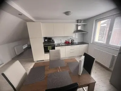 a kitchen with white cabinets and a table and chairs at Ana`s place in Celje