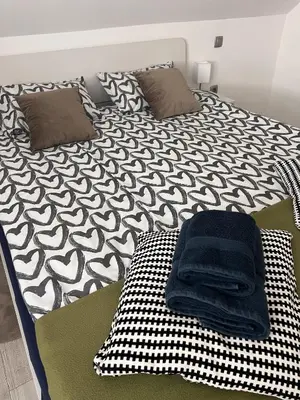 a bed with a black and white comforter on it at Ana`s place in Celje
