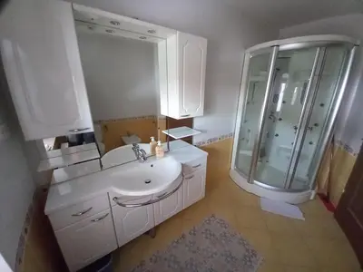 a white bathroom with a sink and a mirror at Apartments Tubej in Bohinj