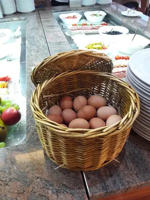 a basket of eggs on a table with plates at Terme Zreče – Hotel Atrij in Zreče