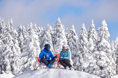 a man and woman sitting on a sled in the snow at Terme Zreče – Hotel Atrij in Zreče