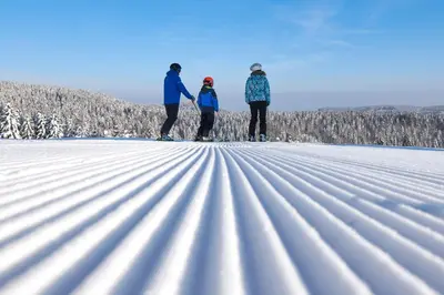 three people standing on skis in the snow at Terme Zreče – Hotel Atrij in Zreče