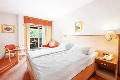 a bedroom with a large white bed and a chair at Terme Banovci - Hotel Zeleni Gaj in Banovci