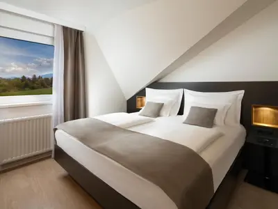 a bedroom with a large bed with a large window at Ahotel Ljubljana in Ljubljana