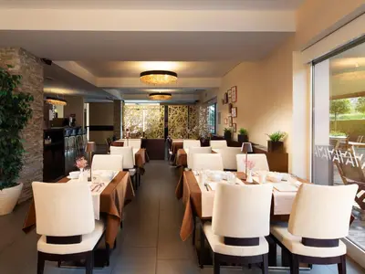 a restaurant with wooden tables and white chairs at Ahotel Ljubljana in Ljubljana