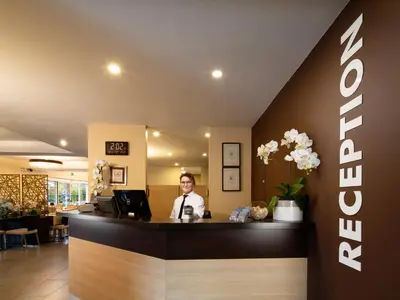 a man sitting at a counter in a hotel lobby at Ahotel Ljubljana in Ljubljana