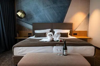 a hotel room with a bed with two wine glasses at Safir Hotel Casino in Sežana