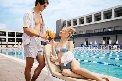 a man and woman sitting on a lounge chair by a pool at Hotel Vivat in Moravske Toplice