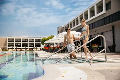 two young men walking down a rail next to a swimming pool at Hotel Vivat in Moravske Toplice