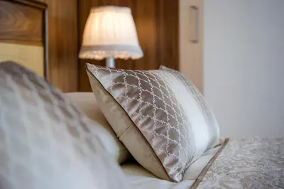 a pillow sitting on a bed with a lamp at Grand Hotel Donat Superior & Wellness Center in Rogaška Slatina
