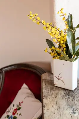 a white vase with yellow flowers on a wooden table at Country House Zunko in Jelovec