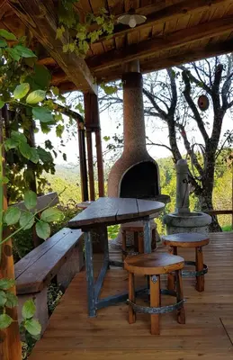 a picnic table and bench on a wooden deck with a stove at Apartma Lipek in Pristava
