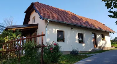 a white house with a red roof and a fence at Apartma Lipek in Pristava