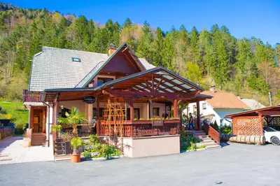 a house in the mountains with a car parked in front at Guesthouse Veranda in Mojstrana