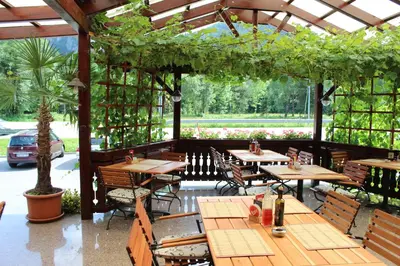 a restaurant with wooden tables and chairs in a pavilion at Guesthouse Veranda in Mojstrana