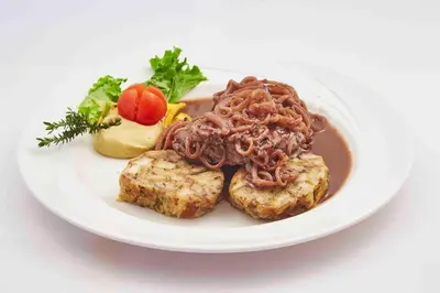 a white plate of food with meat and sauce at Guesthouse Veranda in Mojstrana