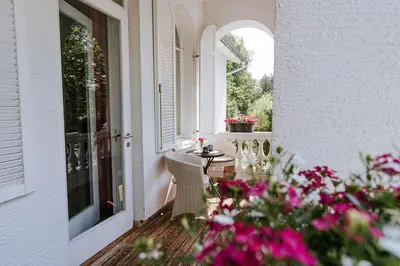 a porch with a table and chairs and flowers at Penzion Vila Prešeren in Bled