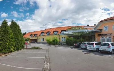 a parking lot in front of a building with cars parked at Penzion Plac ob železnici in Loče pri Poljčanah