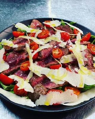 a plate of food with meat and tomatoes on a table at Penzion Plac ob železnici in Loče pri Poljčanah