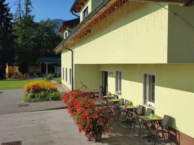a patio with tables and chairs and flowers next to a building at Apartment Jelovca - in the attic in Radovljica