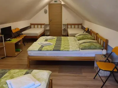 a room with two beds and a desk and chairs at Apartment Jelovca - in the attic in Radovljica