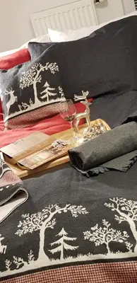 a bed with a black and white blanket with a glass of wine at Apartments Vijolica on the ski slope with free parking in Kranjska Gora