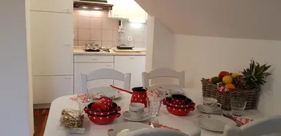 a kitchen with a table with red cups and plates at Apartments Vijolica on the ski slope with free parking in Kranjska Gora