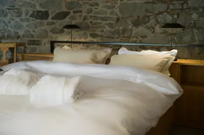 a large bed with white sheets and pillows at Kambra in Dutovlje