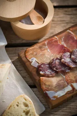 a wooden table with a plate of food and bread at Kambra in Dutovlje