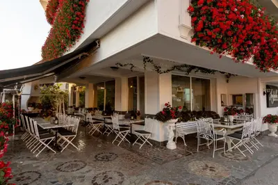a restaurant with white tables and chairs and flowers at Jagodic Garni Hotel in Cerklje na Gorenjskem