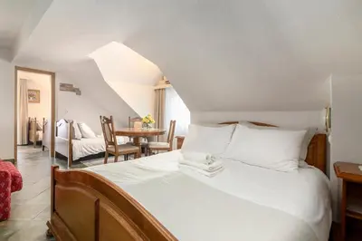 a bedroom with a white bed with a table and chairs at Jagodic Garni Hotel in Cerklje na Gorenjskem