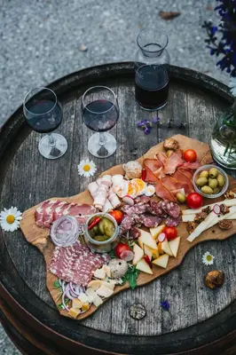 a plate of food on a wooden table with wine glasses at Gostilna Logar in Hotemaže