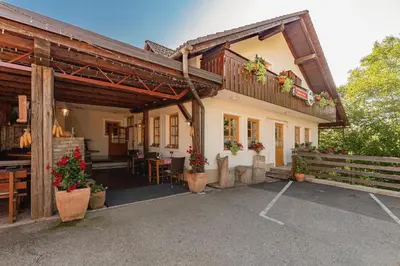 a house with a porch with a table and chairs at Gostilna Logar in Hotemaže
