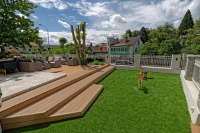 a backyard with a wooden deck and green grass at Hiša Ančka, Boutique Hotel & Maja Rooms in Slovenj Gradec