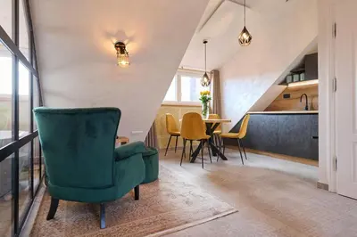 a living room with a green chair and a table at Hiša Ančka, Boutique Hotel & Maja Rooms in Slovenj Gradec
