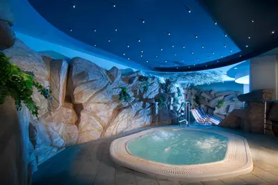 a hot tub in a room with a rock wall at Terme Topolsica - Hotel Vesna in Topolšica