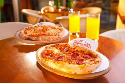 two pizzas sitting on a table with two glasses of orange juice at Terme Topolsica - Hotel Vesna in Topolšica
