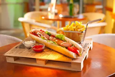 a hot dog on a table with a basket of fries at Terme Topolsica - Hotel Vesna in Topolšica
