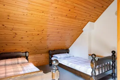 two beds in a room with wooden ceilings at Woodywood house Bohinj in Polje