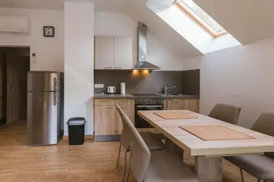 a kitchen with a table and a stainless steel refrigerator at Apartments Dominika in Bohinjska Bela