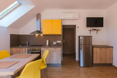 a kitchen with a wooden table and yellow chairs at Apartments Dominika in Bohinjska Bela