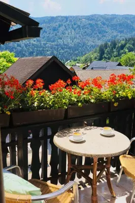 a table and chairs on a balcony with flowers at Pension MOYCHI in Bled