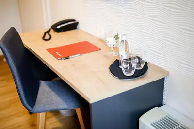 a wooden desk with a laptop and a red folder at Ambient Hotel in Domžale