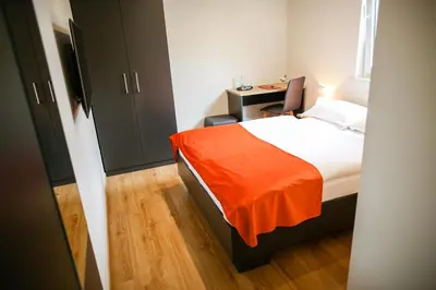 a bedroom with a bed with an orange blanket on it at Ambient Hotel in Domžale