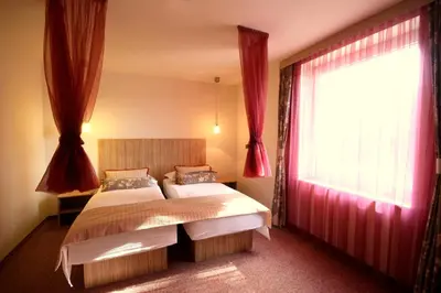 a bedroom with two beds and a window with red curtains at Ambient Hotel in Domžale