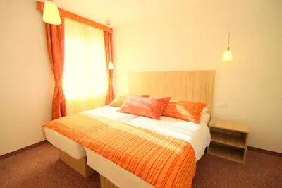 a bedroom with a bed with an orange and white blanket at Ambient Hotel in Domžale