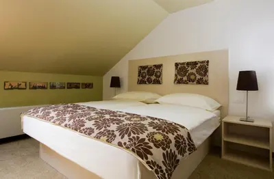 a bedroom with a large bed and two pictures on the wall at Ambient Hotel in Domžale