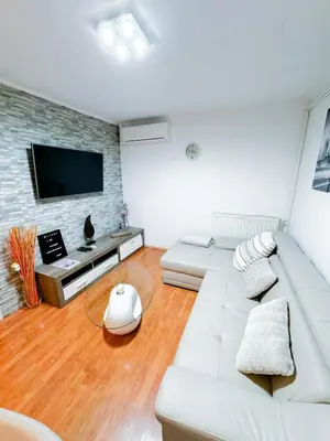 a living room with a white couch and a tv at Apartments Šentvid in Ljubljana